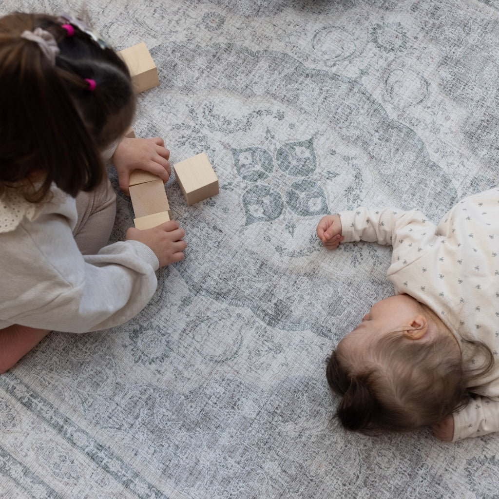 Two children play on an extra large grey Persian rug-style play mat