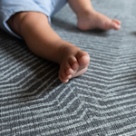 Baby feet are supported on the grijs speelmat designed from birth to keep floor play protected and safe 