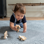 Baby crawls across a textile inspired floor mat  playing with a trio of wooden play cars perfect for baby floor play 