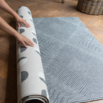 Hands unroll the double sided tapis de jeu for family floor play 