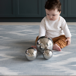 Baby playing with sensory metallic balls on Light blue and beige play mat with subtle diamond design inspired by ikat motifs ideal for family living spaces