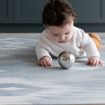 Baby playing with sensory toy on A practical playroom rug The Totter and Tumble play mats have a wipeable surface so you can keep your home clean and tidy and it can look stylish as well 