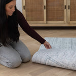 A lady pulls back a large reversible play mat to show a beautiful subtle rug pattern on the reverse