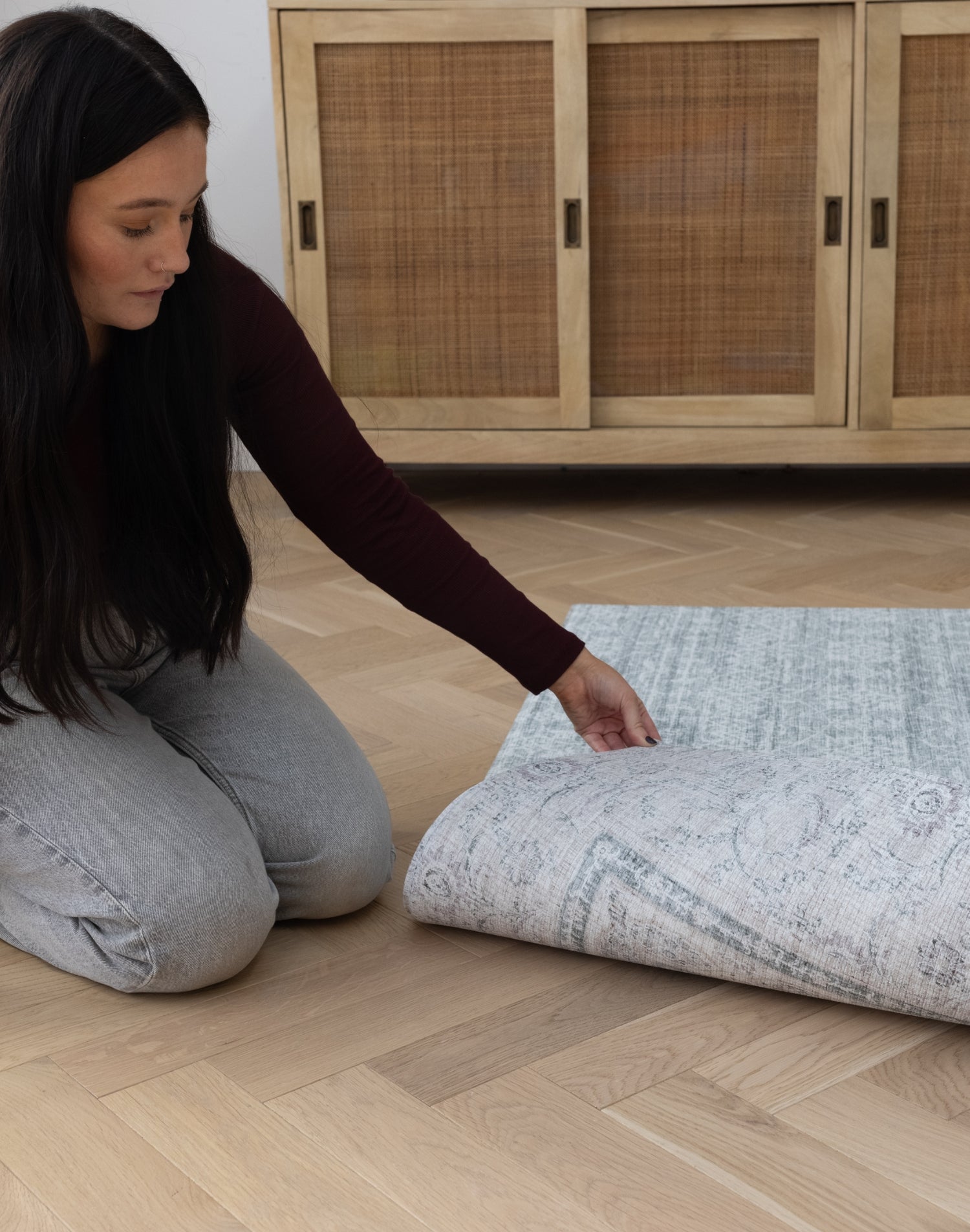 A lady pulls back a large reversible play mat to show a beautiful subtle rug pattern on the reverse