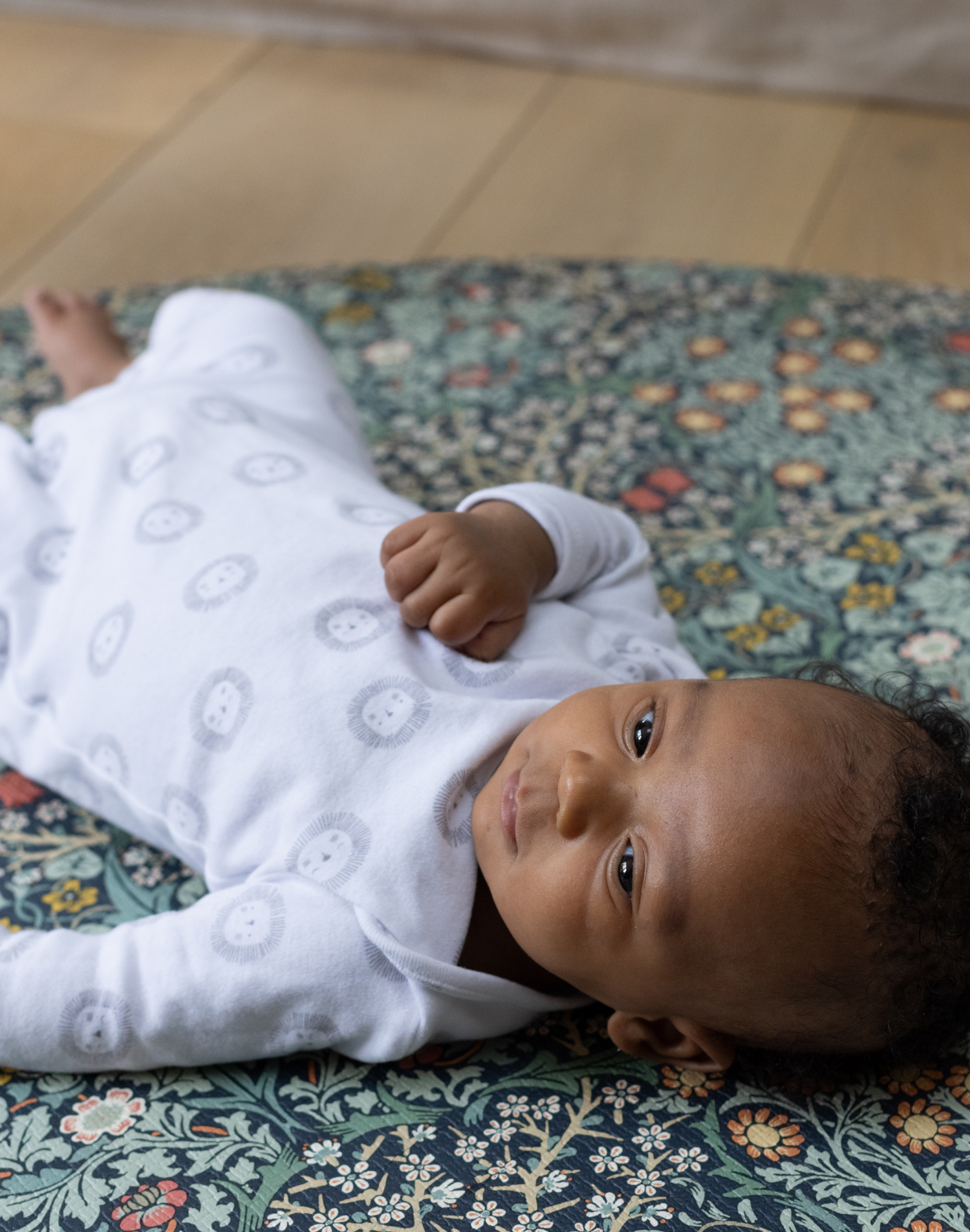 blackthorn round play mat from totter + tumble happy baby relaxing on floor mat in morris & co double-sided designs baby playmat foam non toxic and safe from newborn