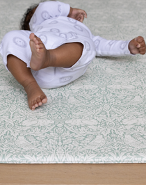 totter + tumble thick padded playmat with baby resting on floor mat made from memory foam kids play rug in morris & co brer rabbit print beautiful rug alternative for the family home wipe down and reversible designs