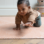 Little boy plays on crawling mat by totter and tumble with a modern orange design 