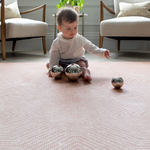 Little girl plays with sensory toys on the Totter and Tumble Tapis designed for safe play in the home 