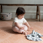 Baby enjoys playing on thick padded floor mat with a sensory black and white muslin 