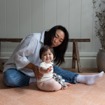 Baby and lady sit comfortably on thickly padded play mat with a modern kilim design 