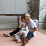 Baby and toddler enjoy floor play on padded foam mat with stylish orange design 