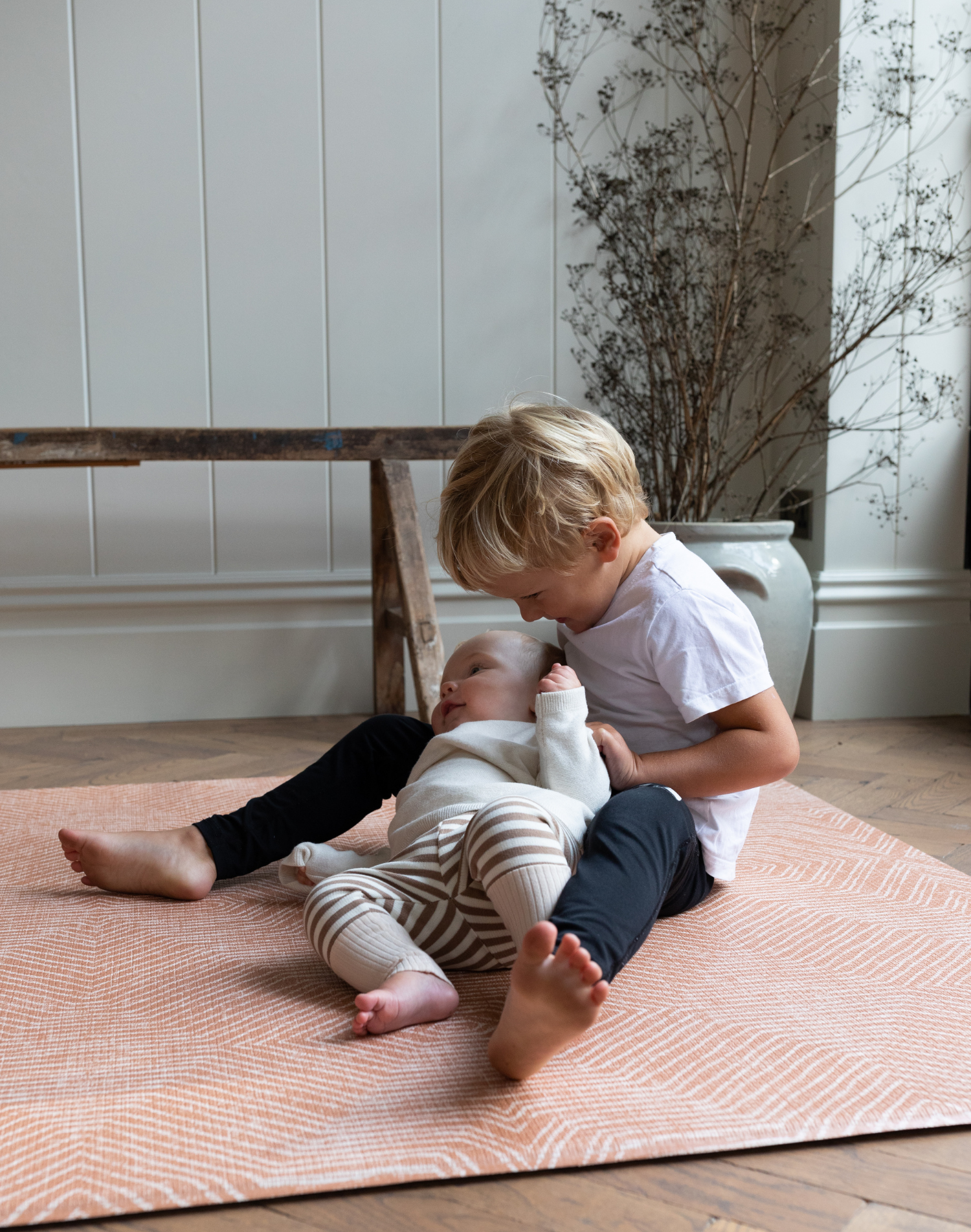 Baby and toddler enjoy floor play on padded foam mat with stylish orange design 