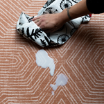 Parents using soft cloth to wipe spilled milk off sealed, waterproof totter and tumble play mats