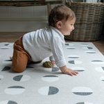 Toddler crawls across a graphic play mat made from luxury memory foam for added support.