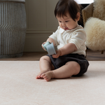 baby plays with stacking cups protected on alfombra de juego elegante