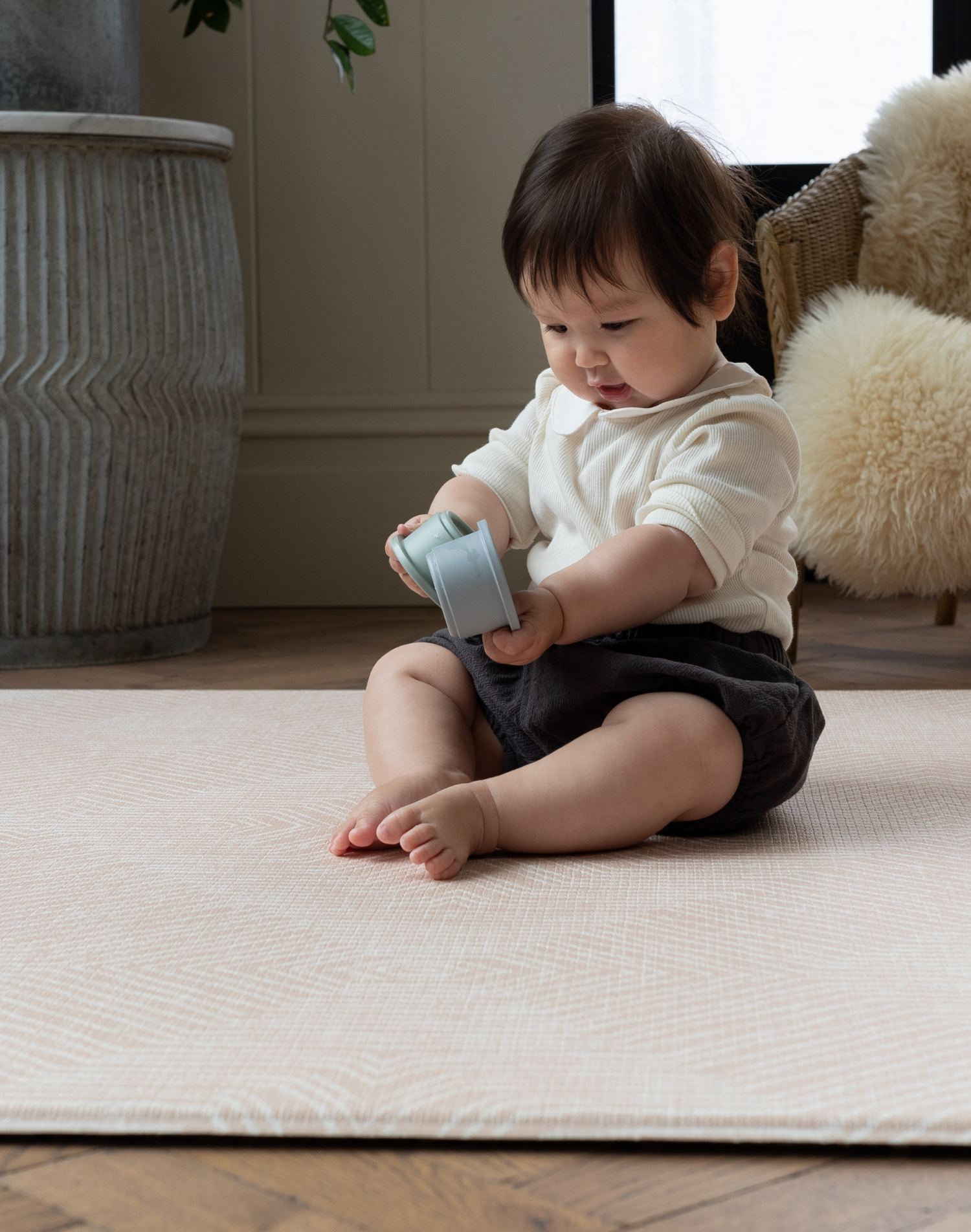 baby plays with stacking cups protected on alfombra de juego elegante