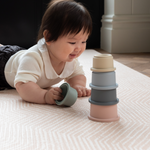 Little girl enjoys floor play with stacking cups on roze speelmat with gentle kilim textile design 