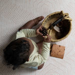 Little boy explores natural sensory basket for stimulation with thickly padded baby mat for a safe surface underneath 