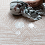 Wiping up milk with muslin on waterproof baby playmat 