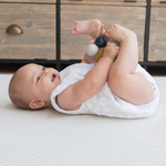 XSmiley baby laying comfortably on thick Kilim play rug designed for babies, adults and stylish family homes 