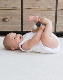 XSmiley baby laying comfortably on thick Kilim play rug designed for babies, adults and stylish family homes 