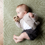 Baby plays on a baby play mat with a thick design to support on the floor during rolling and tummy time 