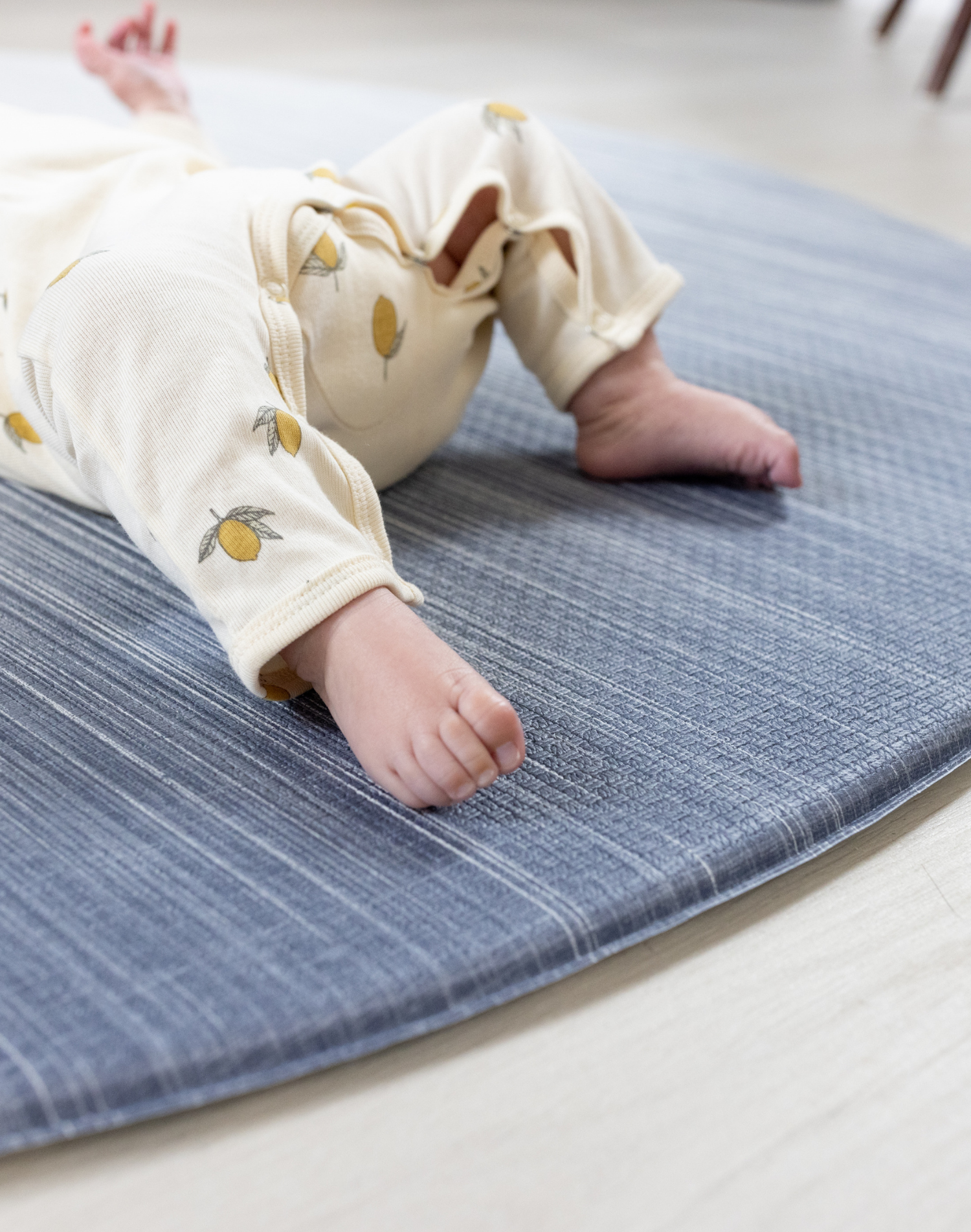 Close up of babies feet on The Kasuri a large padded floor mat by Totter and Tumble adds a stylish appeal to the space it is unrolled in with a one piece design that is washable so spillages are easy to clean the perfect play rug for the home