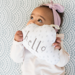 Baby resting on baby play mat with subtle scalloped pattern playing with soft toy 