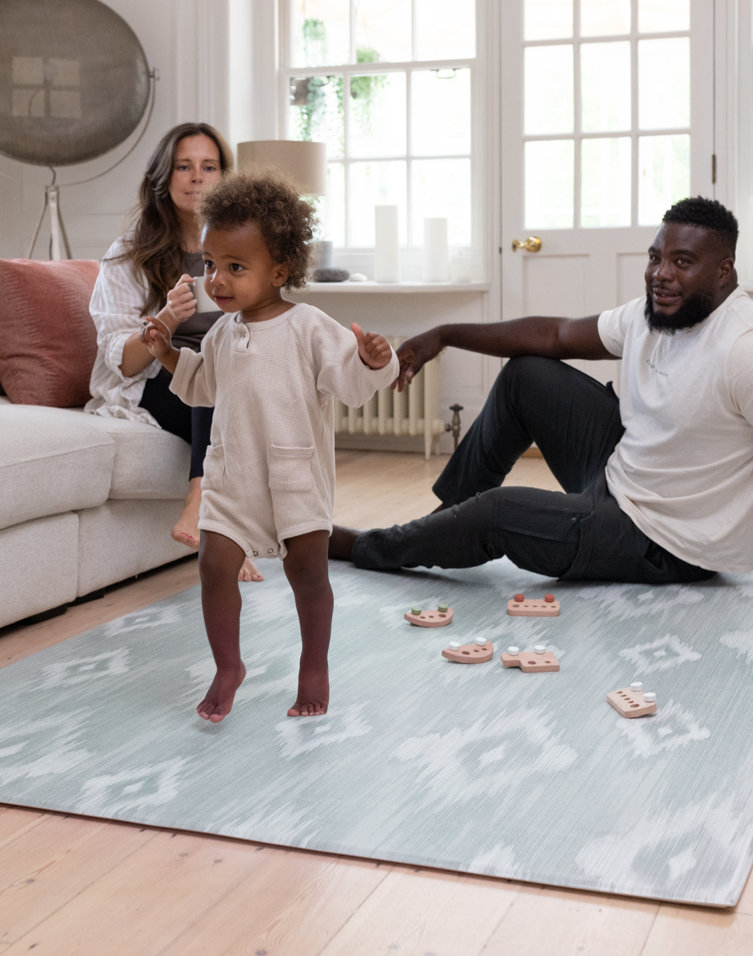 Family enjoying time together on The Odissi Totter & Tumble play mat is designed to look stylish in family homes with a sophisticated green and beige ikat design to complement modern decor