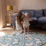 baby and parents playing on elegant round playmat in living room
