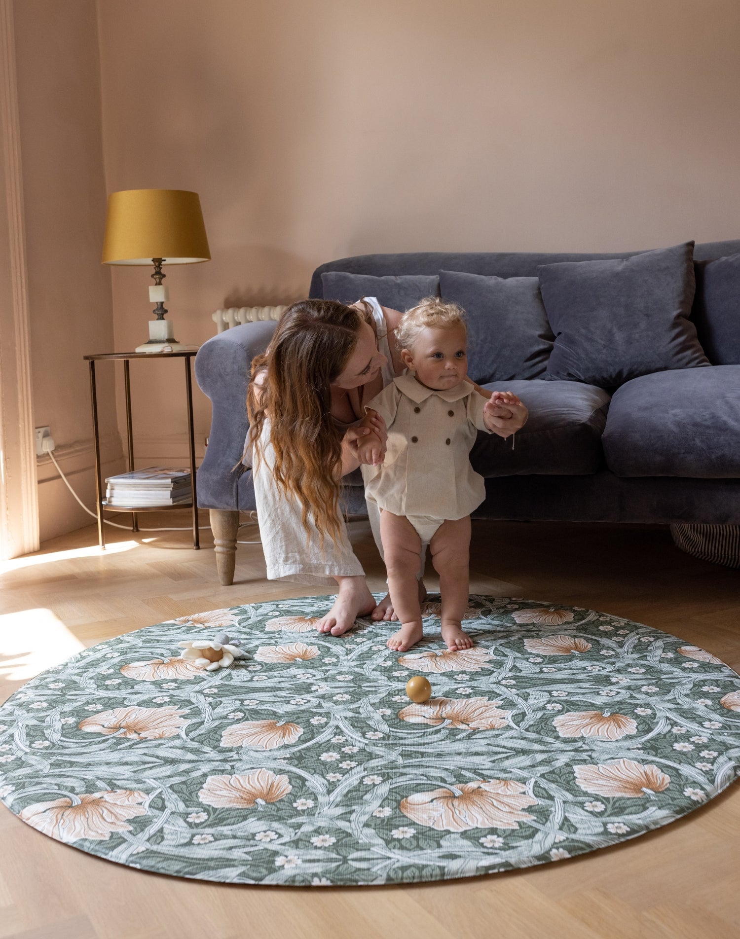 baby and parents playing on elegant round playmat in living room
