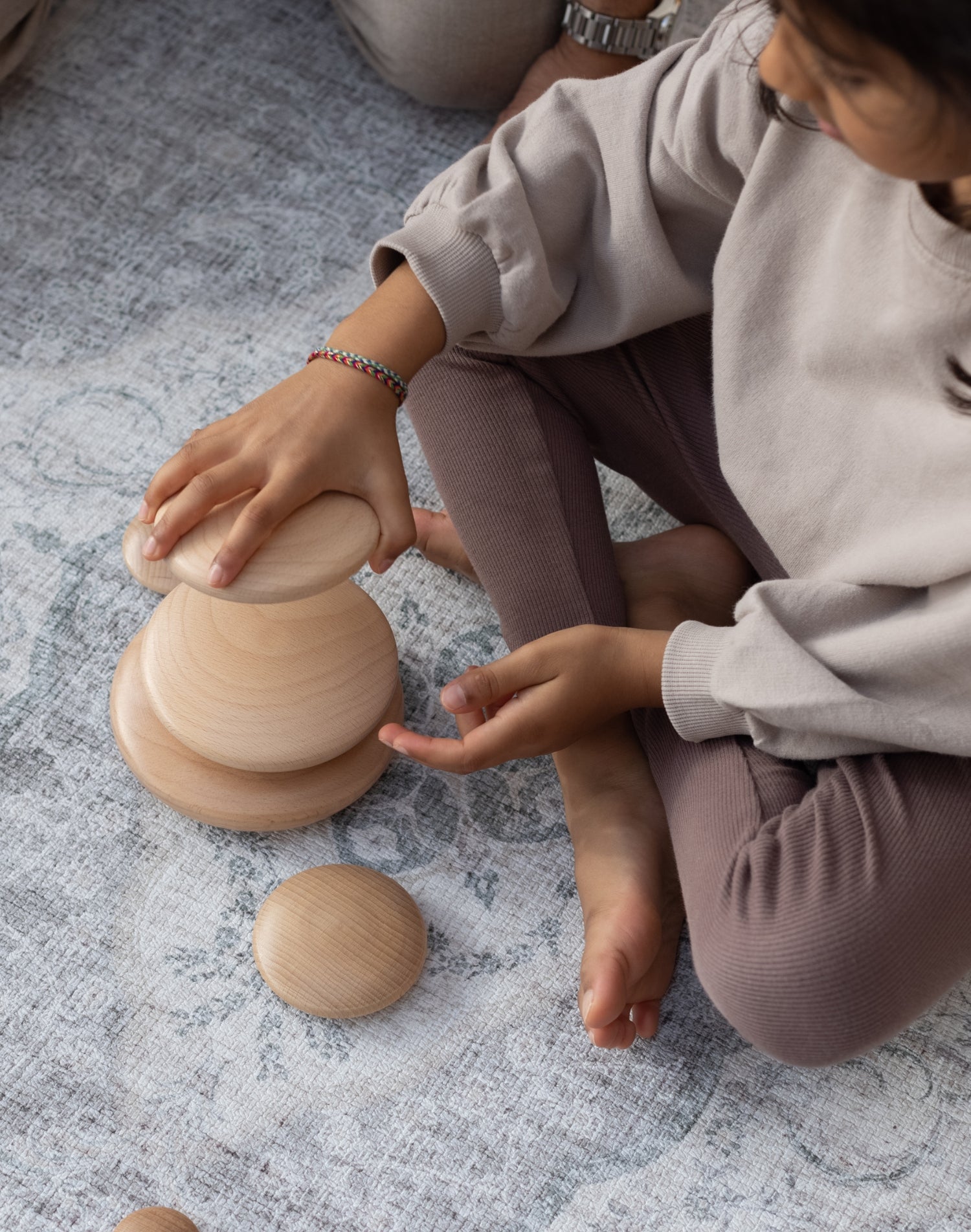 A child plays with stacking toys on a large foam playmat