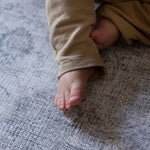 baby feet lie on a soft play mat that looks like a rug