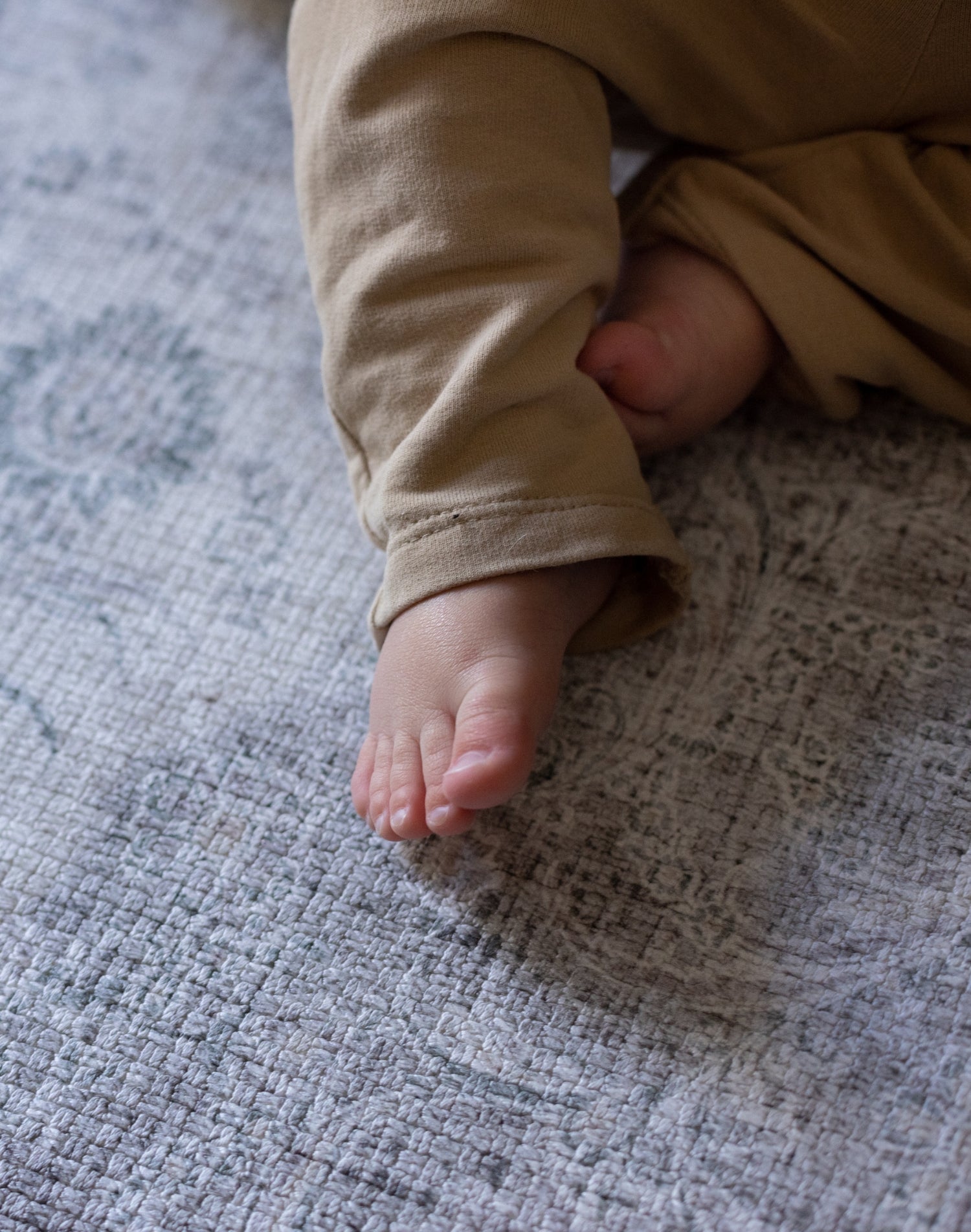 baby feet lie on a soft play mat that looks like a rug