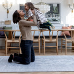 A mum lifts up her child while they play on a large floor mat for the living room. They are both smiling and laughing