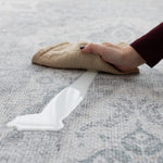 A hand cleans up a milk spillage with a soft cloth on large waterproof play mat