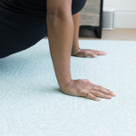 Lady is supported using the exercise mat by Totter and Tumble with a modern botanical design 