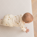 Baby crawling across neutral textured play mat that offers supports through the developmental stages 