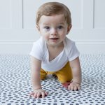 Little baby crawls across crawling mat with textured surface for traction while moving 