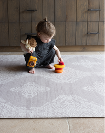 Toddler stacks toys on stable grey play mat with textured design for support and memory foam for protection on tiled flooring large size creates a dedicated play area on the floor