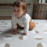 Baby is supported on thick Spelmatta with durable memory foam and organic polka design 