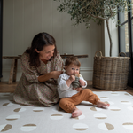 Lady and child sit together on tan one piece play mat with a modern design that looks great in modern living space 