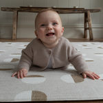 Happy baby enjoys tummy time on baby play mat with durable supportive design 