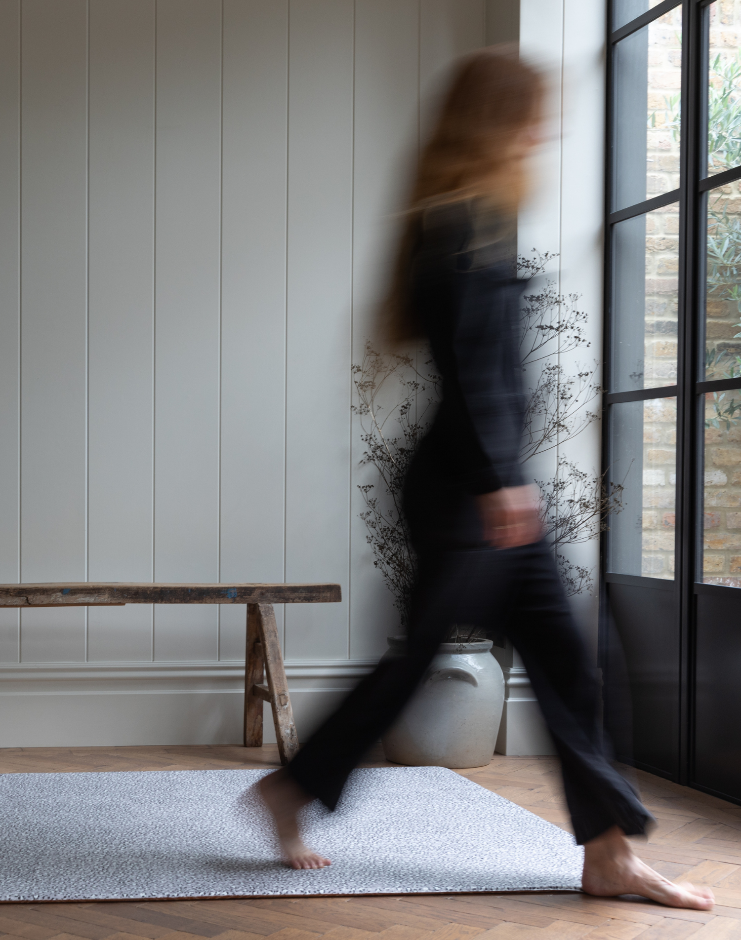 Lady walks across padded baby foam mat with grey leopard print motif that is subtle for the space 