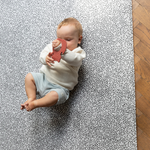 Baby plays on soft foam mat with textured teething toy 