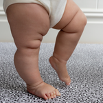 Baby practices standing on foam mat with textured surface for added support 