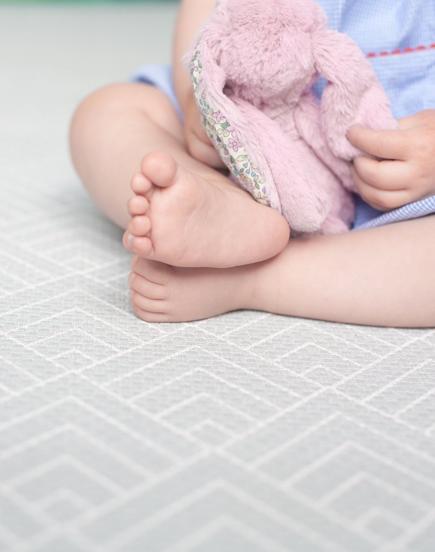 Baby sits safely on non toxic play mat designed from birth with a gentle grey design 