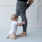 Baby reaches for mums legs on extra large yoga mat with wanderer design by totter and tumble 