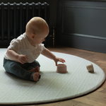 Baby plays with sustainable stacking cups on tapis de jeu rond