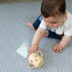 Tapis de jeu "Totter + Tumble" avec bébé assis dessus, lavable à l'eau.